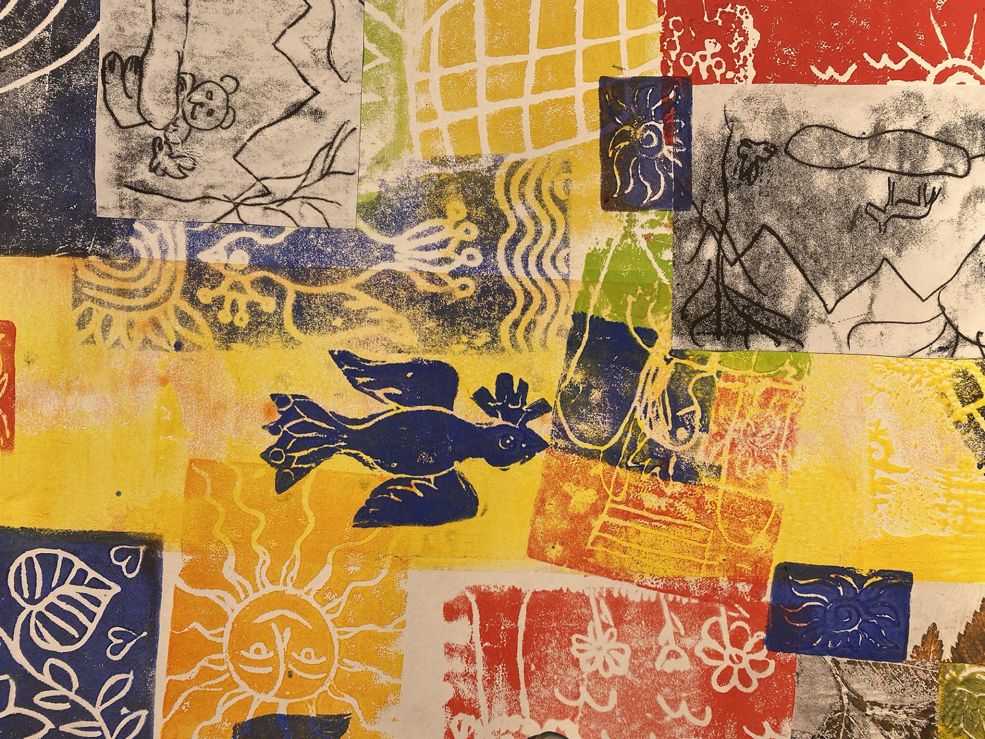 Eine bunte Collage mit abstrakten Drucken und Zeichnungen, darunter ein blauer Vogel, Sonnengesichter, ein Bär, Berge und verschiedene geometrische Muster in Gelb-, Rot-, Blau- und Weißtönen.